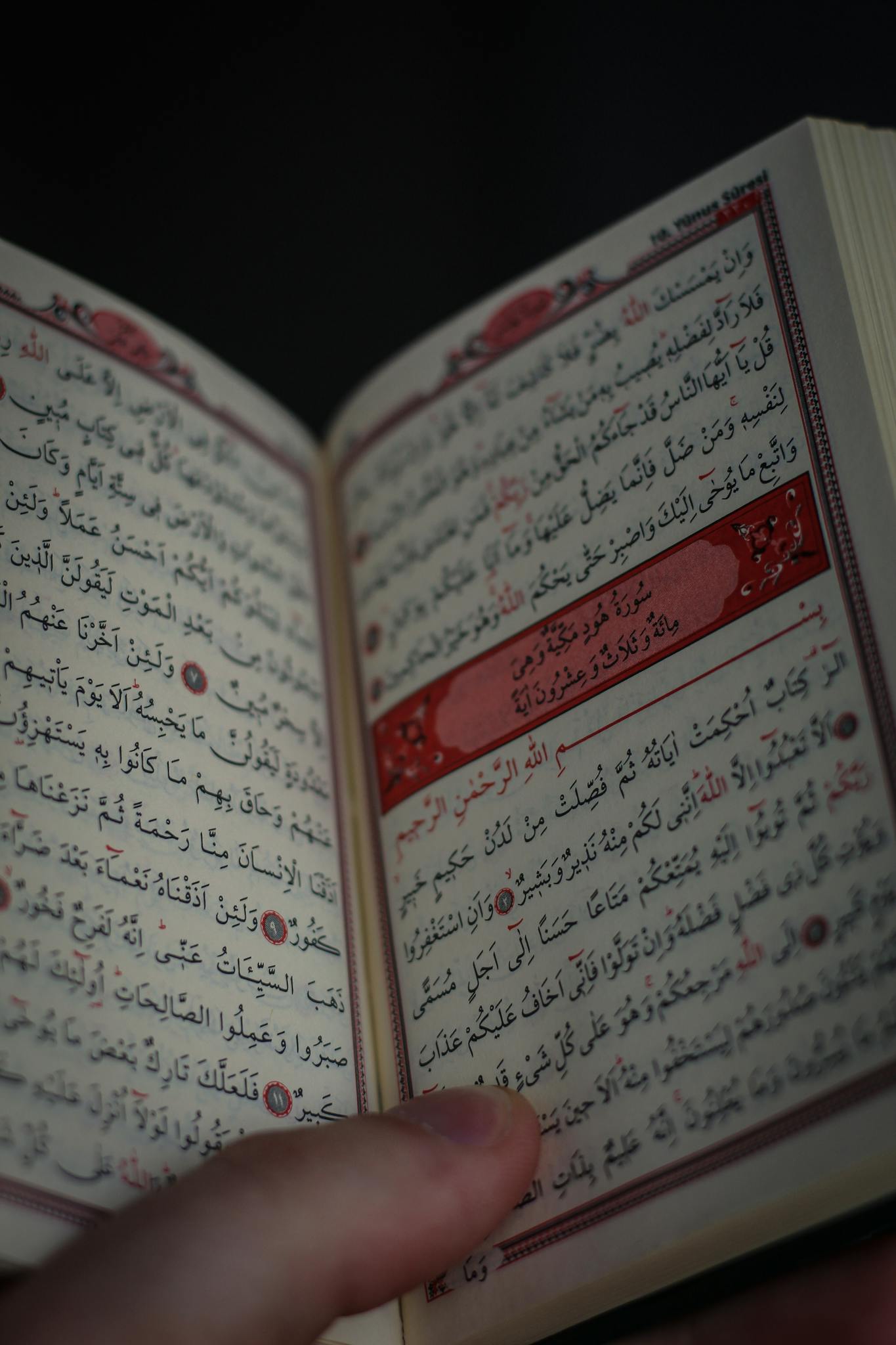 Detailed close-up of a Quran being held open by a hand, showcasing Arabic script.